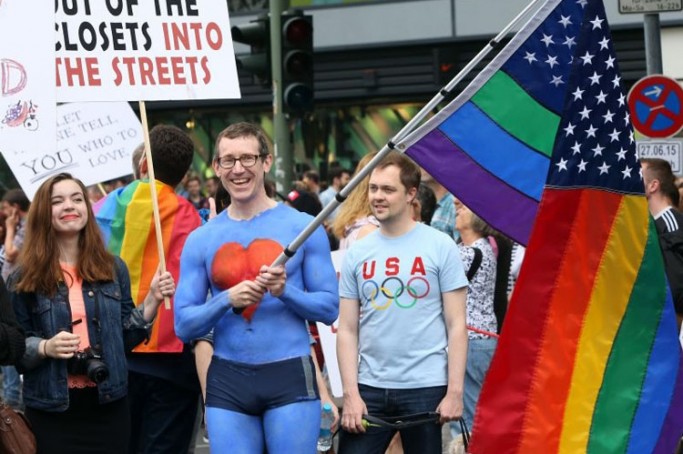 United States embassy employee Tim Standaert waves a rainbow American flag as he attends the Christopher Street Day (CSD) gay parade in Berlin on June 27, 2015.  AFP PHOTO / ADAM BERRY