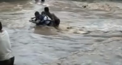 Crianças voltam da escola penduradas em uma corda por conta de estrada inundada