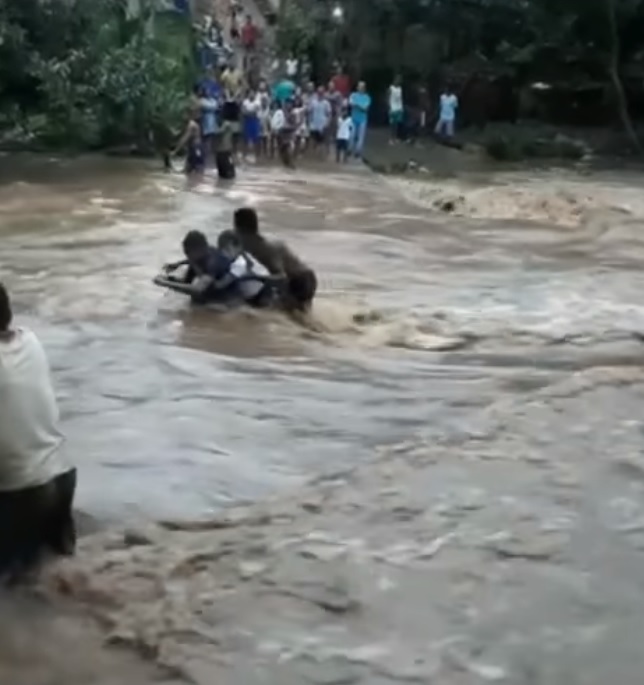 Crianças voltam da escola penduradas em uma corda por conta de estrada inundada