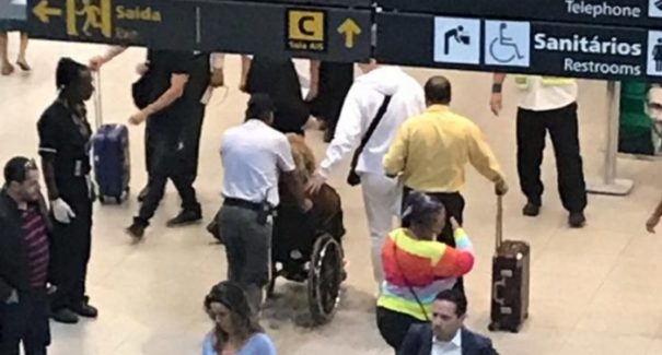 Alcione cai na escada rolante de aeroporto e sai do local em cadeira de rodas