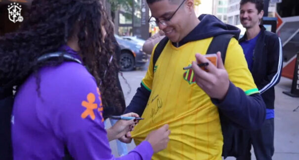 Jovem com camisa do Sampaio ganha autógrafos de jogadoras do Brasil em Montreal