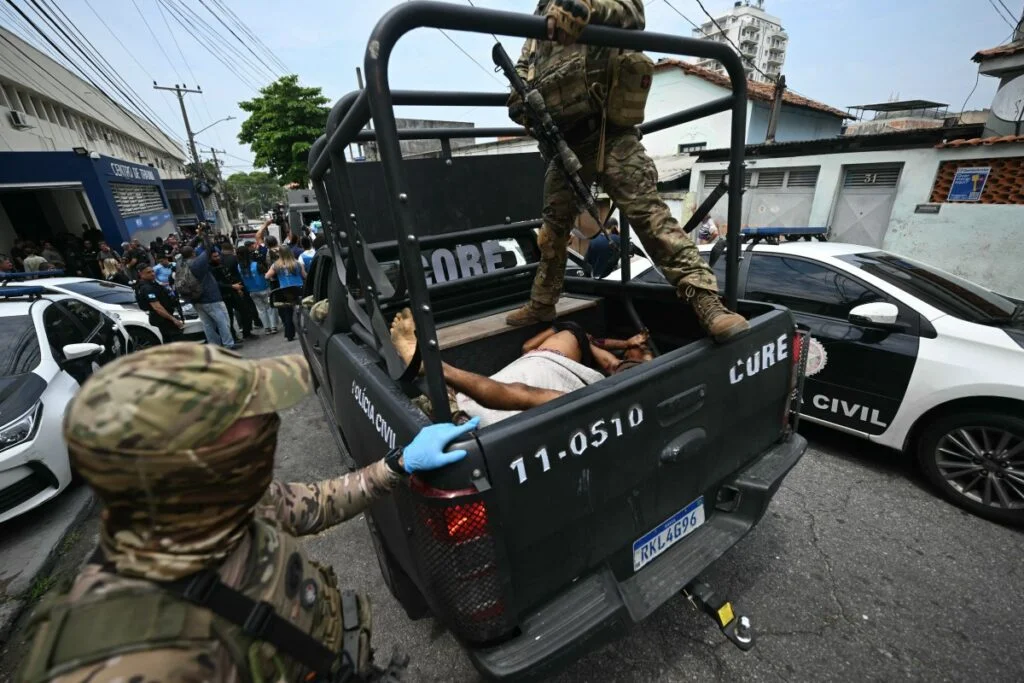 Policiais transportam corpos para um hospital após a Operação Contenção na favela Vila Cruzeiro, no complexo da Penha, no Rio de Janeiro, Brasil, em 28 de outubro de 2025.  (Foto: Mauro PIMENTEL / AFP)