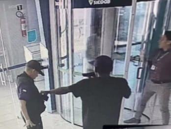 Um dos assaltantes entrou na agência portando um simulacro de arma de fogo e rendeu o segurança (Foto: Câmeras de segurança)
